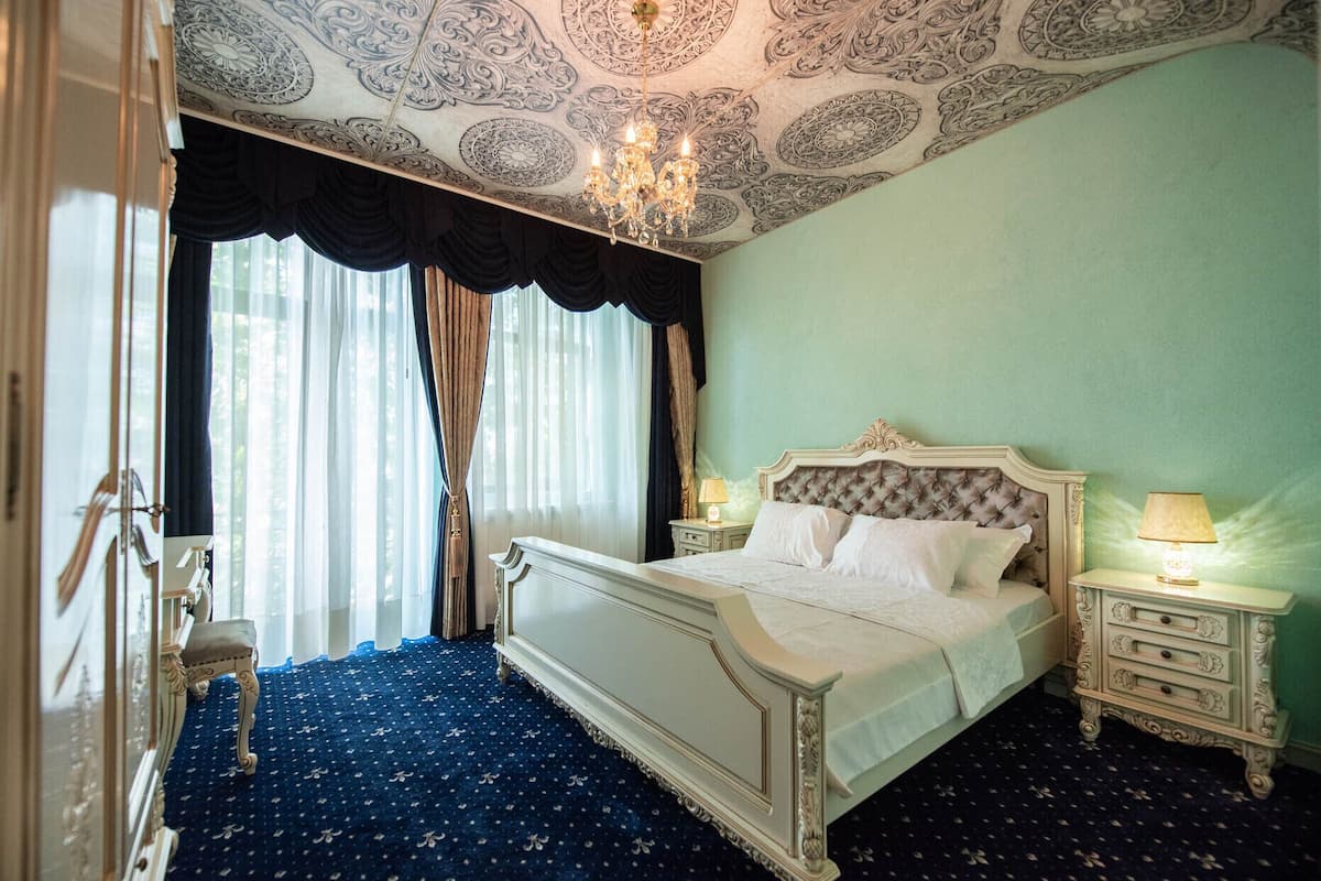 Une chambre à coucher avec un grand lit, un plafond décoré et un lustre.