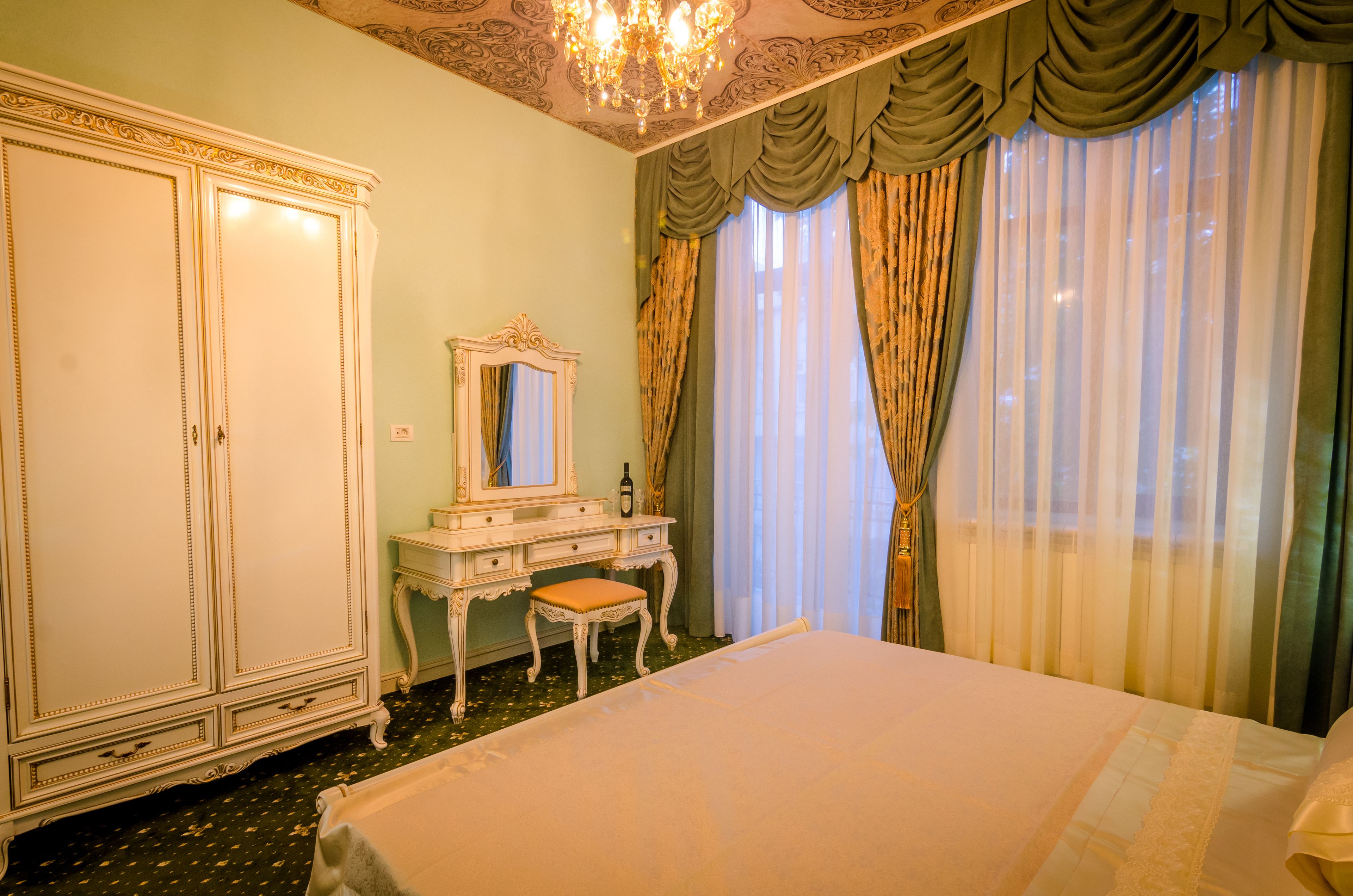A bedroom with a large bed, a dresser with a mirror, and a chandelier.