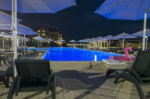 A nighttime swimming pool area with lounge chairs and umbrellas. - WELCOME summer (Zatoka)