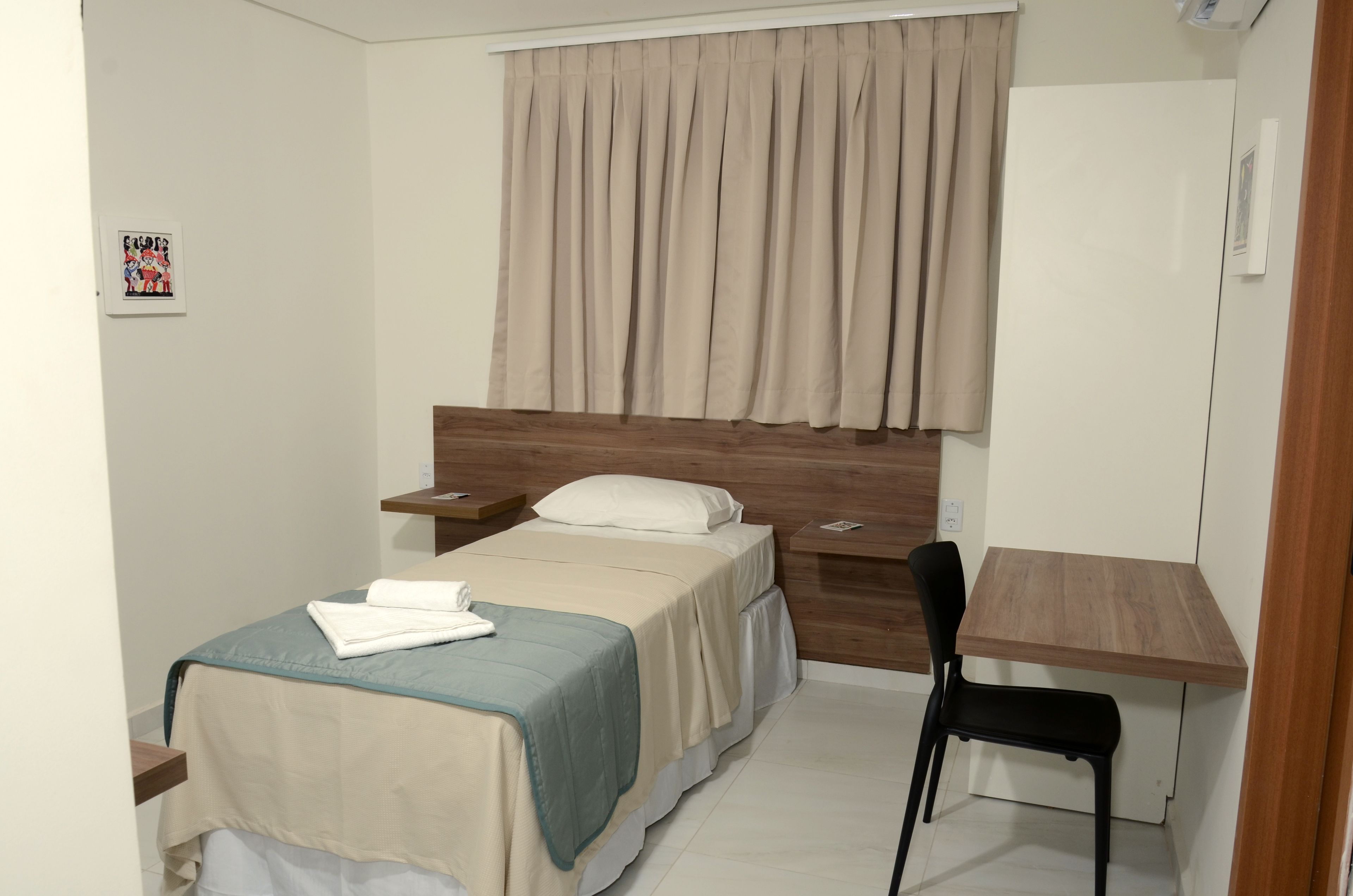 A bedroom with a bed, a desk, and a chair.