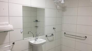 Un baño con lavamanos, espejo y ducha.