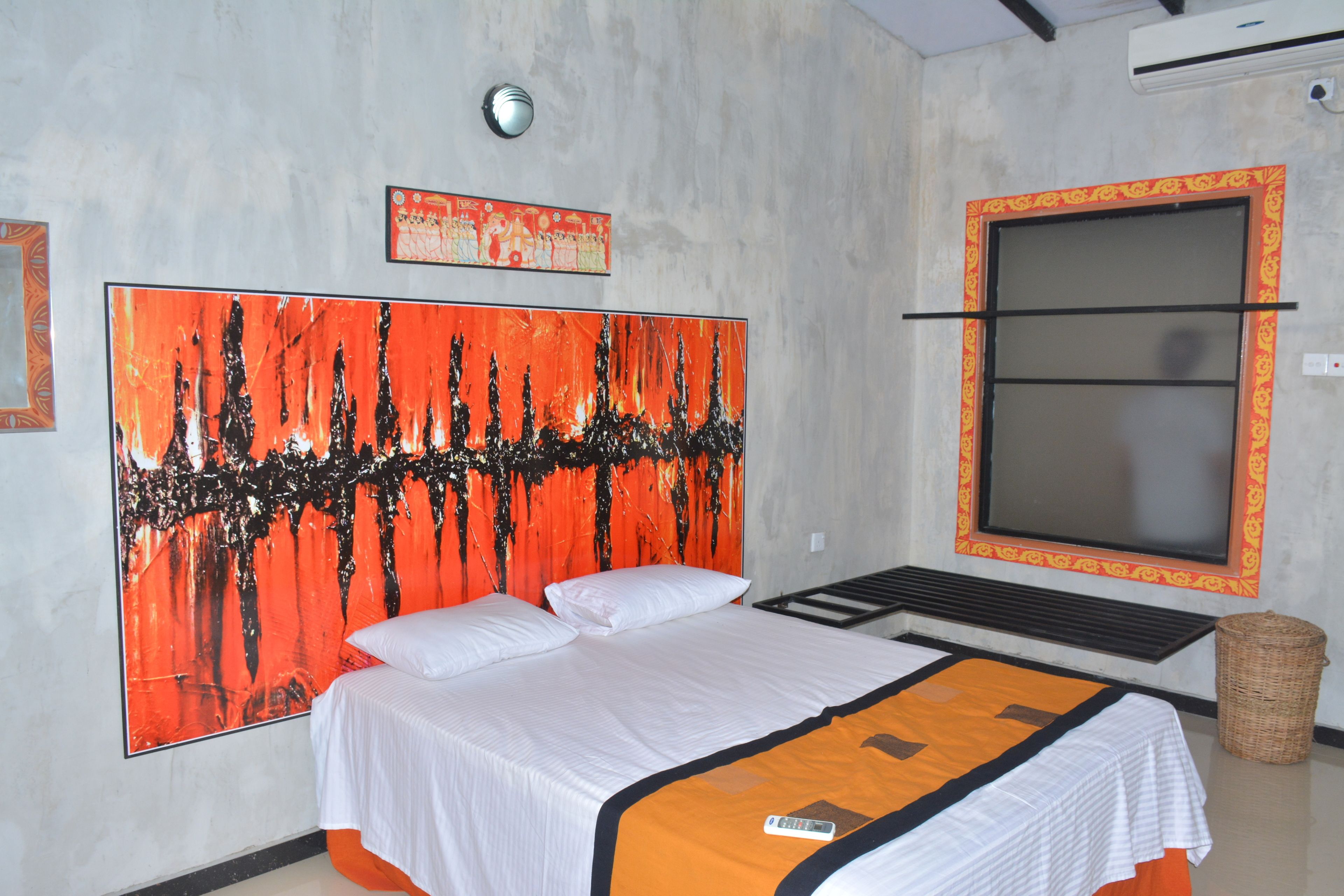 Une chambre d’hôtel avec un grand lit, une fenêtre ornée d’un cadre décoratif et un mur sur lequel est accrochée une grande peinture abstraite.