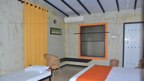 A room with two single beds, a chair, a small table, and a door.
