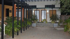 A building with a covered entrance area, multiple doors, and potted plants.