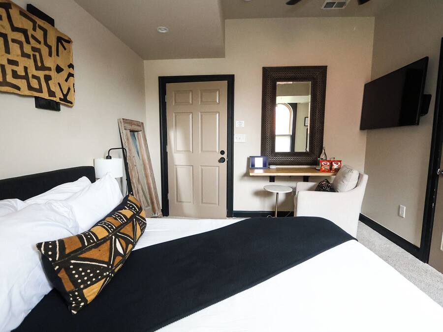 A hotel room with a bed, a small table, a sofa, a mirror, and a TV.