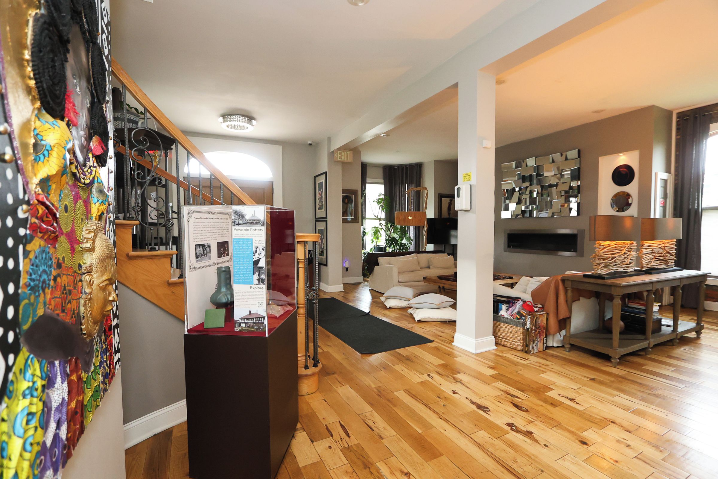 A spacious living area with a wooden floor, a sofa, a coffee table, and a TV. There is a staircase with a railing and a door leading to another room.