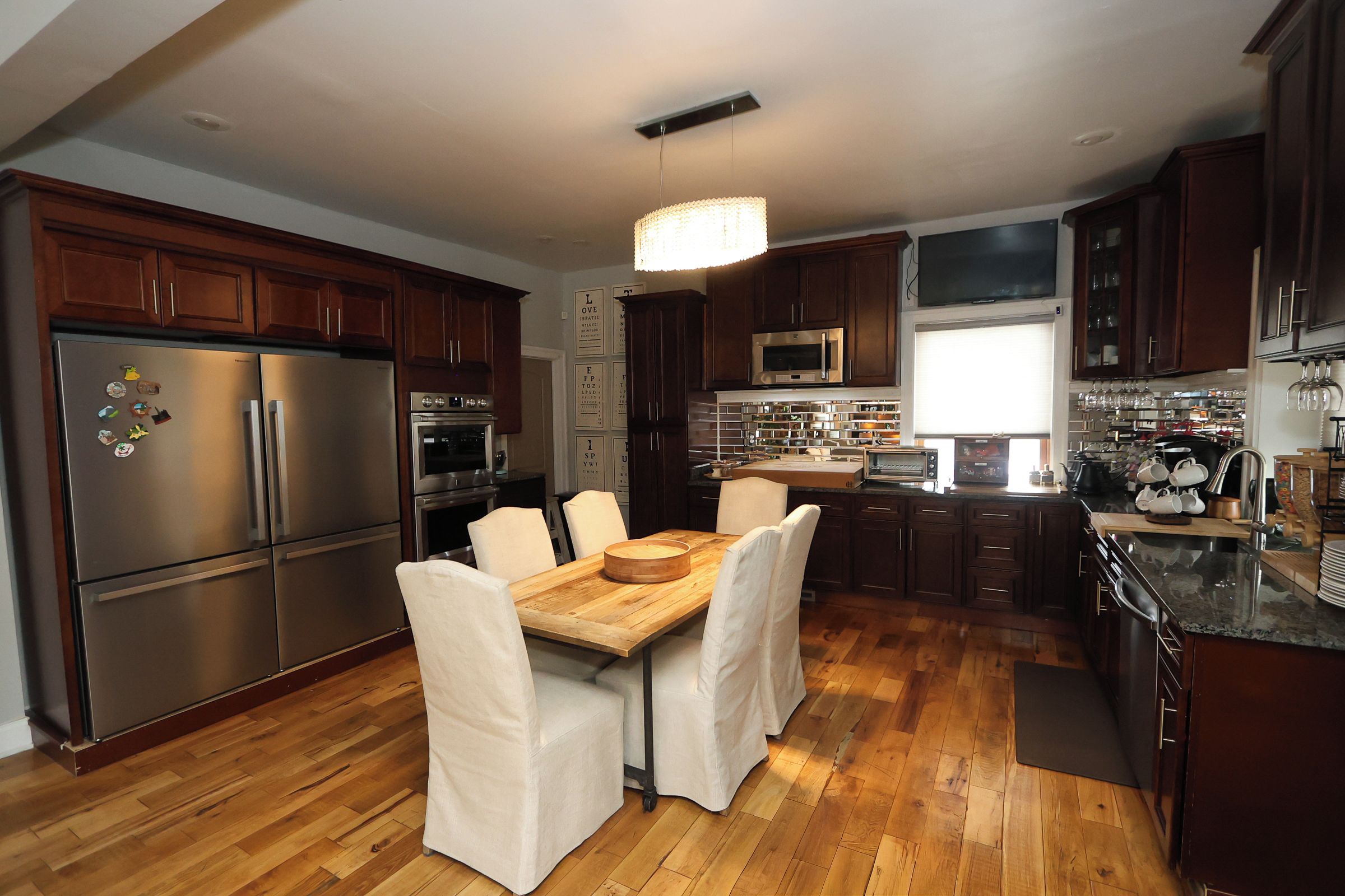 A modern kitchen with stainless steel appliances, wooden cabinets, and a dining area with a wooden table and chairs.