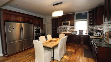 A modern kitchen with stainless steel appliances, wooden cabinets, and a dining area with a wooden table and chairs.