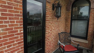 A brick building with a glass door, a metal chair with a cushion, and a decorative lantern.
