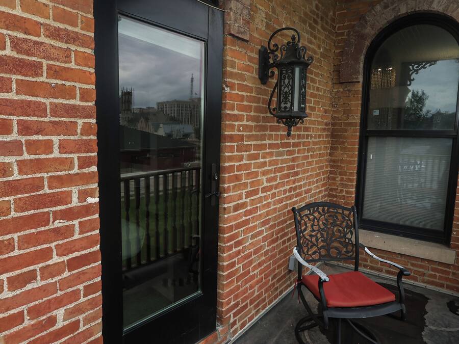 A brick building with a glass door, a metal chair with a cushion, and a decorative lantern.