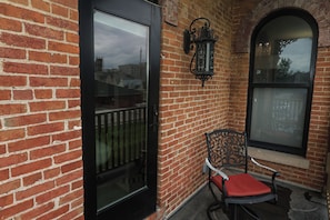 A brick building with a glass door, a metal chair with a cushion, and a decorative lantern. - The Cochrane House Luxury Historic Inn (Detroit)