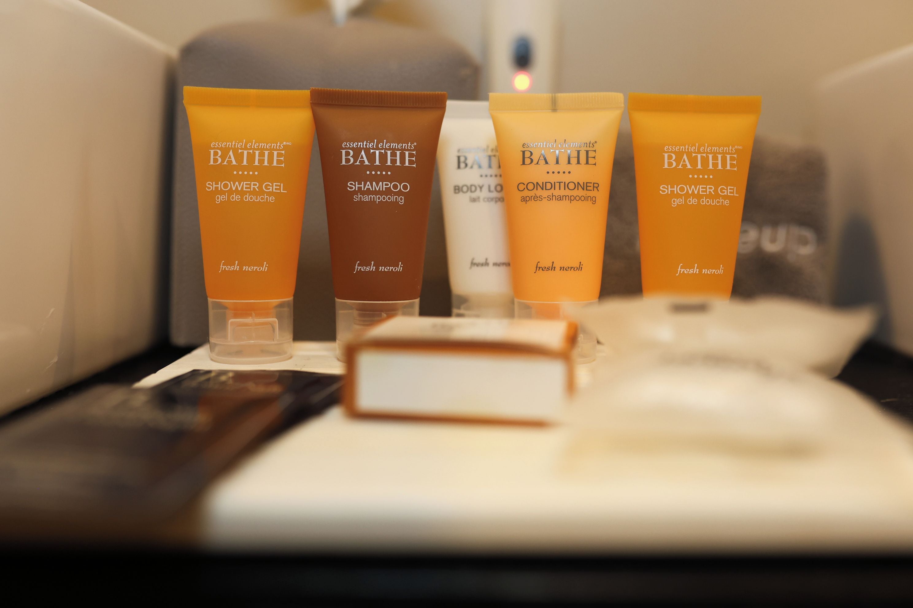 Une étagère de salle de bain contenant quatre produits de toilette : un gel douche, un shampooing, un après-shampooing et un autre gel douche.