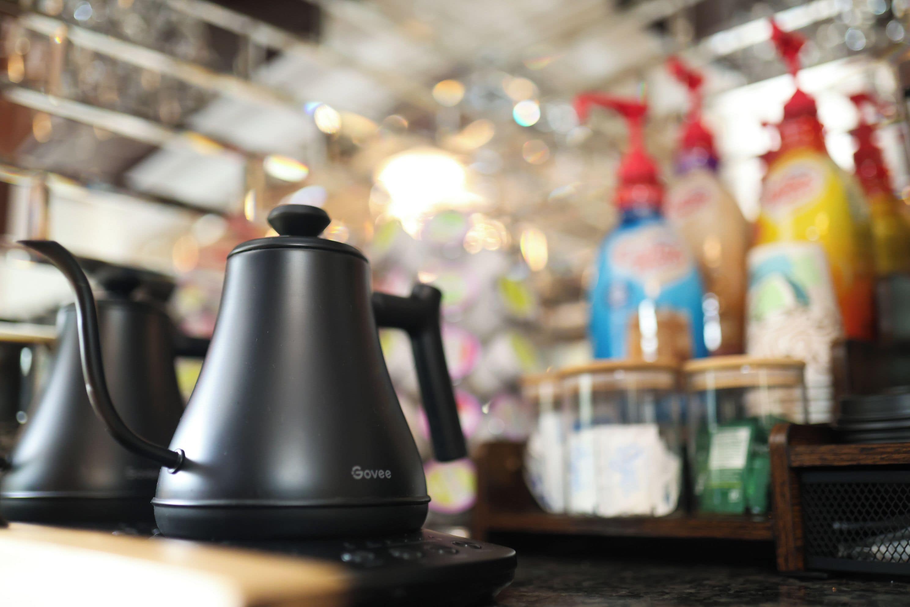 A kitchen area with a black electric kettle and a coffee pot on a countertop.