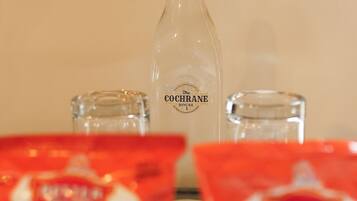 A bottle of COCHRANE, two glasses, and two packets of snacks on a table.