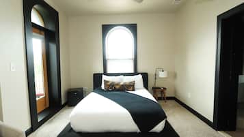 A hotel room with a bed, a window, a ceiling fan, and a nightstand.