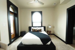 A hotel room with a bed, a window, a ceiling fan, and a nightstand.