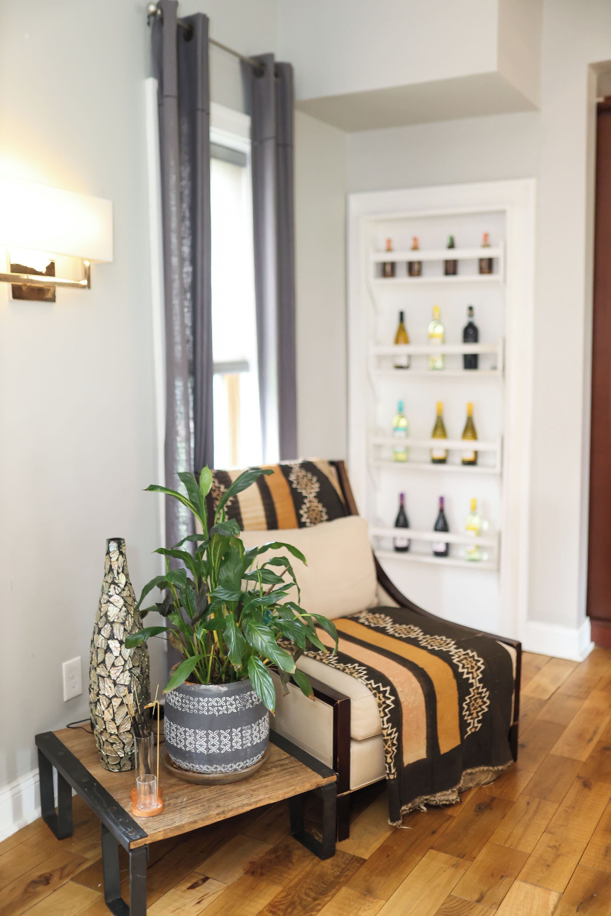 A living room with a sofa, a side table with a plant, and a bookshelf with various items.