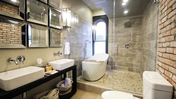 A modern bathroom with a large mirror, two sinks, a toilet, and a shower area.