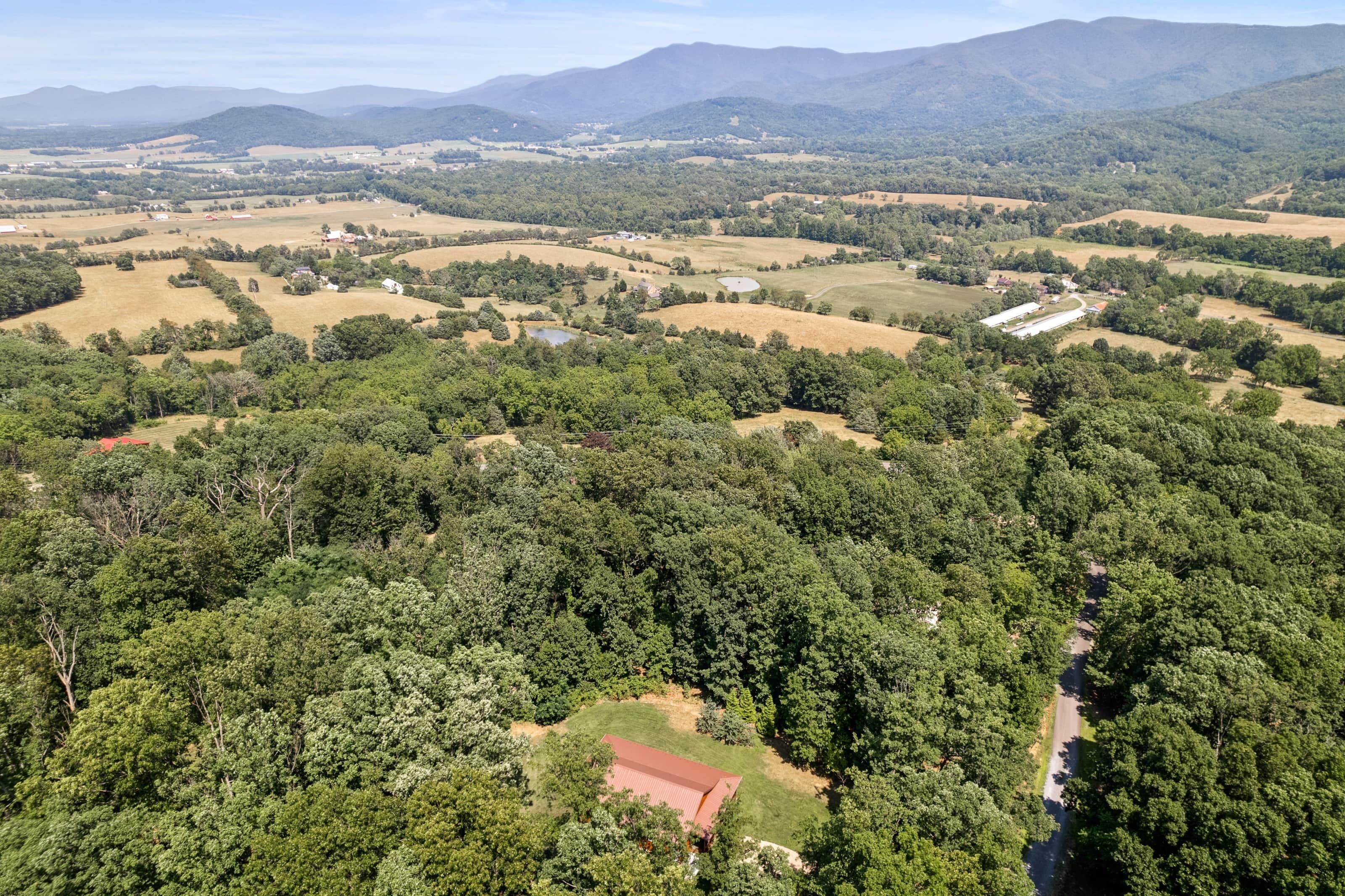 An aerial view of a rural landscape with fields, trees, and a few buildings.