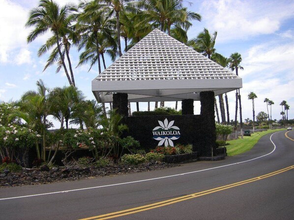 A gazebo with a sign reading "WAIKOLOA" surrounded by palm trees and a curved road. - The PERFECT Vacation Condo, close to beaches, shopping, discounted golf (Waikoloa)