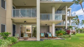 A multi-story building with balconies, outdoor seating, and a well-maintained garden. - The PERFECT Vacation Condo, close to beaches, shopping, discounted golf (Waikoloa)