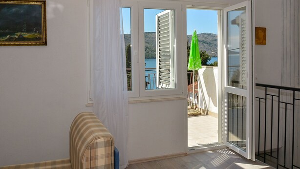 Una habitación con vista a un lago y montañas, una puerta corrediza de vidrio, un sofá a rayas y un cuadro en la pared.