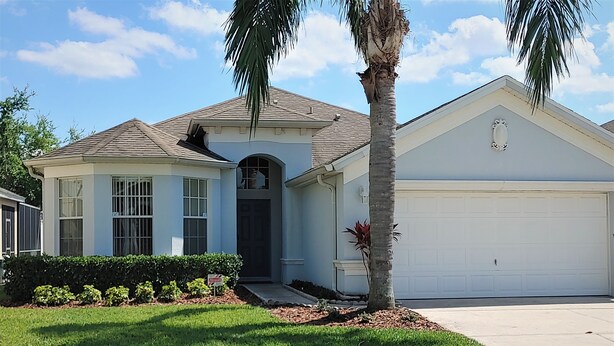 A single-story house with a garage, a front entrance, and a well-maintained lawn. - Stay in Luxury, Private Pool/Spa, Games Room, Close to Disney and Golf (Haines City)