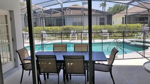 A covered outdoor area with a pool, lounge chairs, and a table with chairs. - Stay in Luxury, Private Pool/Spa, Games Room, Close to Disney and Golf (Haines City)