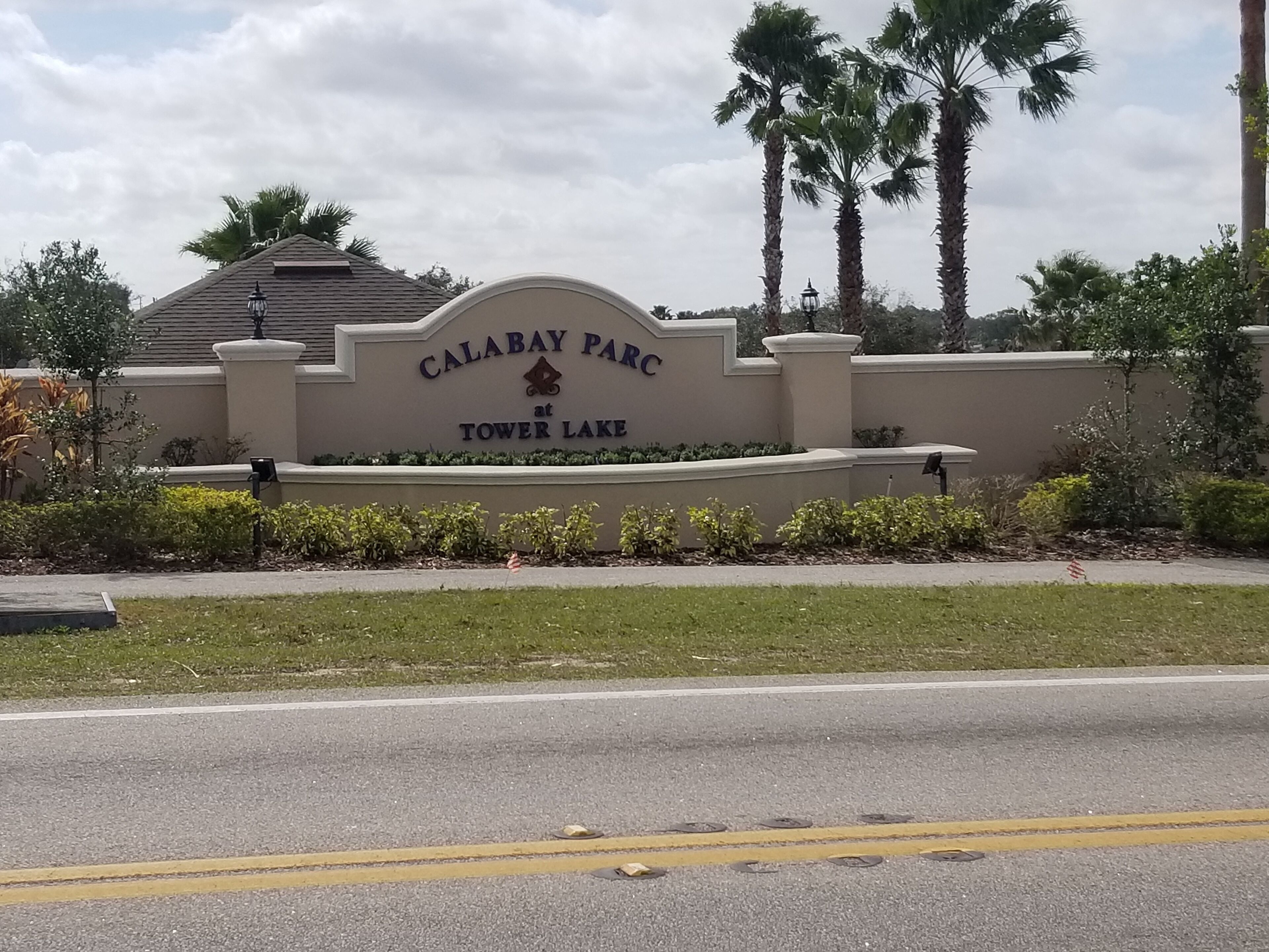 Señal de Calabay Park en Tower Lake, con una entrada ajardinada y palmeras.