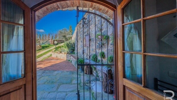 An open wooden door leading to a stone pathway with a metal gate. - Esclusivo per te (COLLE VAL D' ELSA)