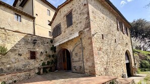 A stone building with a wooden door, a small bench, and a paved courtyard. - Esclusivo per te (COLLE VAL D' ELSA)