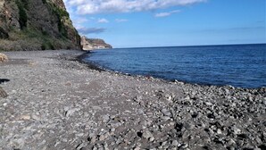 Una playa rocosa con un acantilado y un cielo despejado.