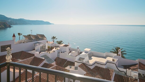 Ein Küstenhotel mit terrakottafarbenen Dächern, einem Poolbereich und Blick aufs Meer.