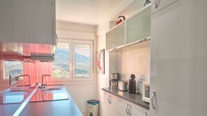 Eine Küche mit einer langen Arbeitsplatte, einem Fenster mit Blick und einem Mülleimer.