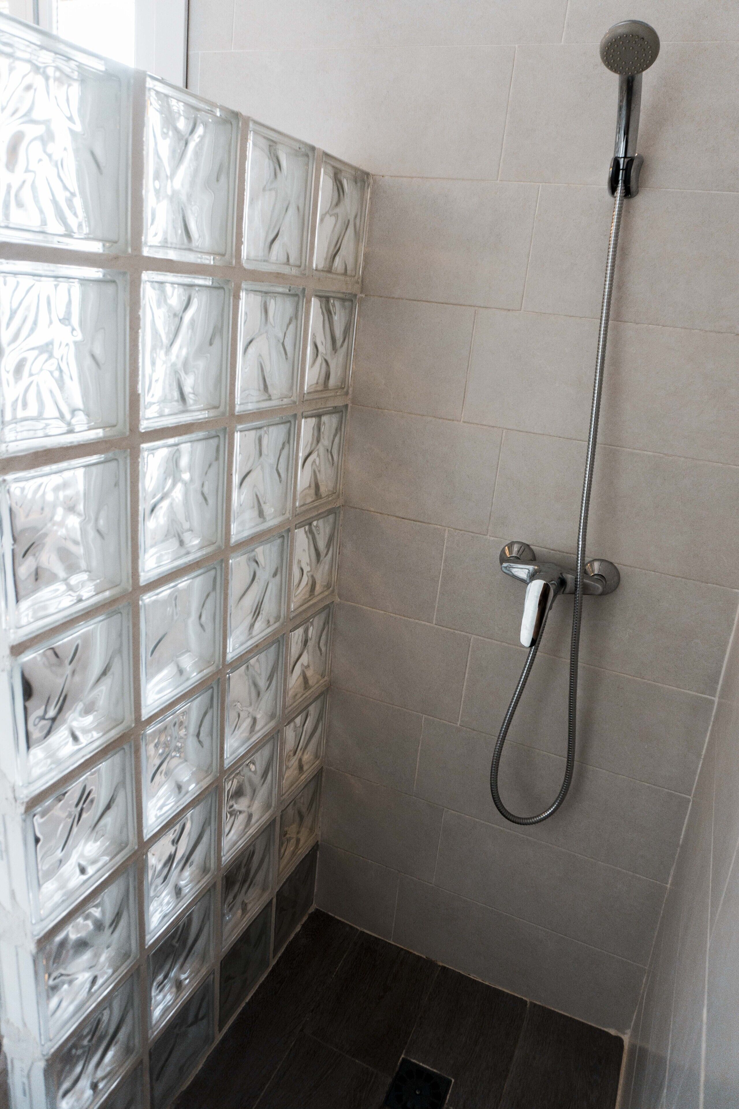 Een douche met een douchekop en een wand van glasblokken.