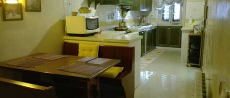 Cocina compacta con comedor, que incluye una mesa pequeña, sillas y electrodomésticos básicos.