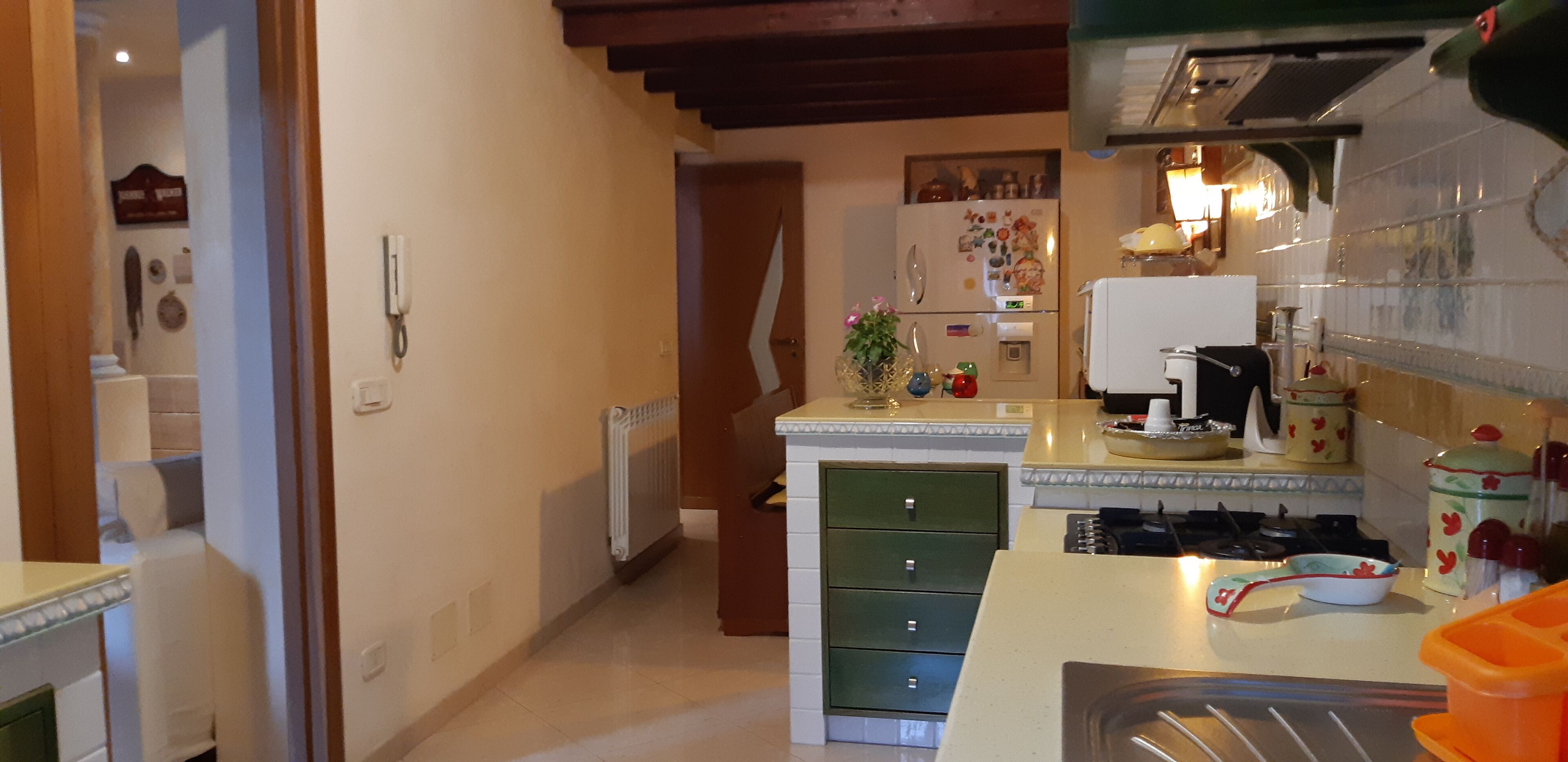Una cocina equipada con refrigerador, estufa y varios electrodomésticos. Hay una encimera con un lavamanos y una ventana encima.