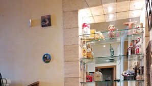 Una cocina con encimera de mármol, un mueble de madera y un estante de vidrio con diversos objetos.