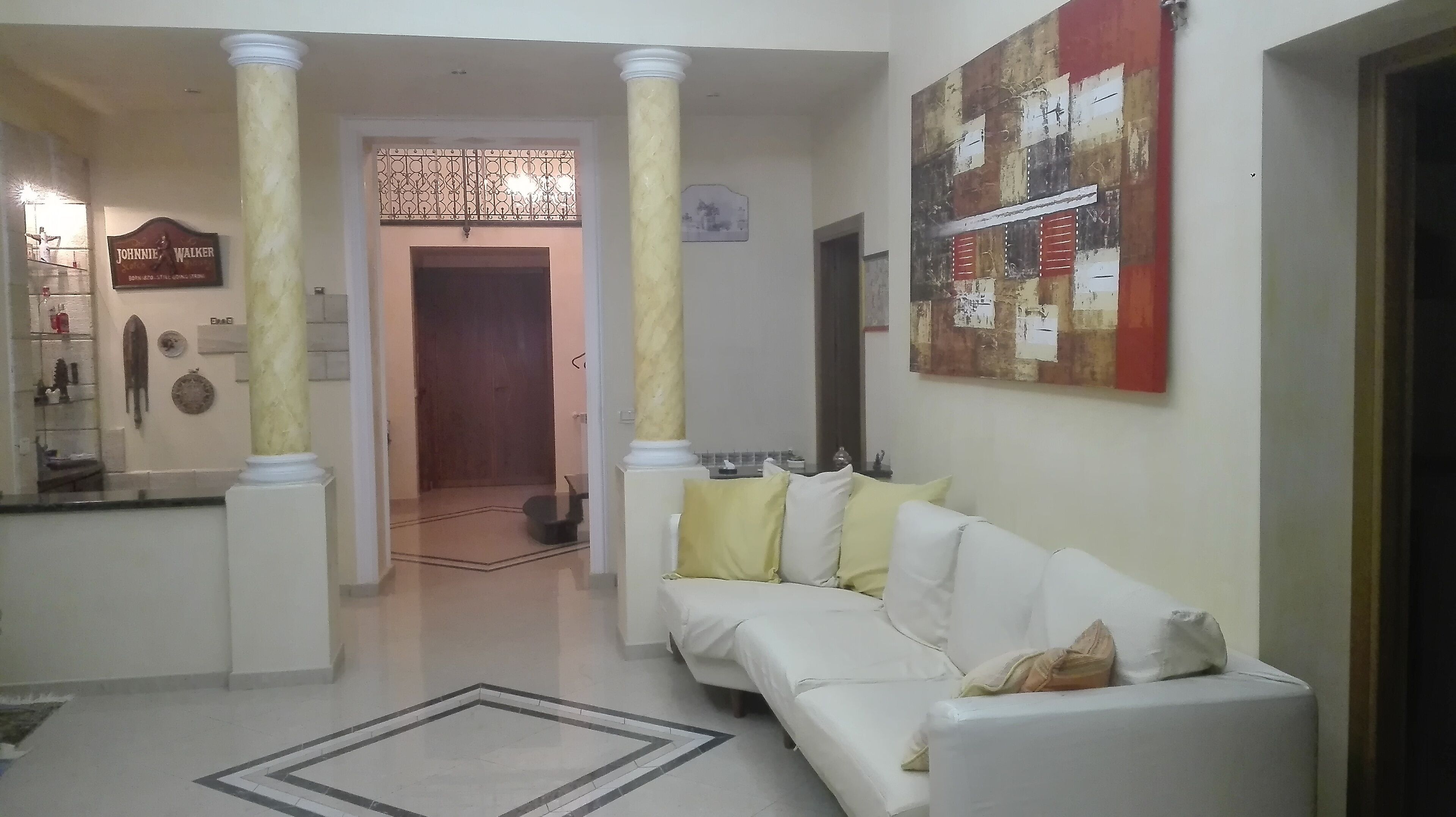 A hallway with a white sofa, a decorative mirror, and a wall with a red and white abstract painting.