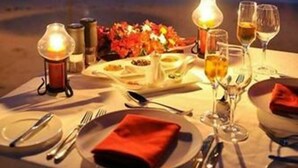 A table set for two on a beach with a view of the ocean. - Evasion (Gressier)