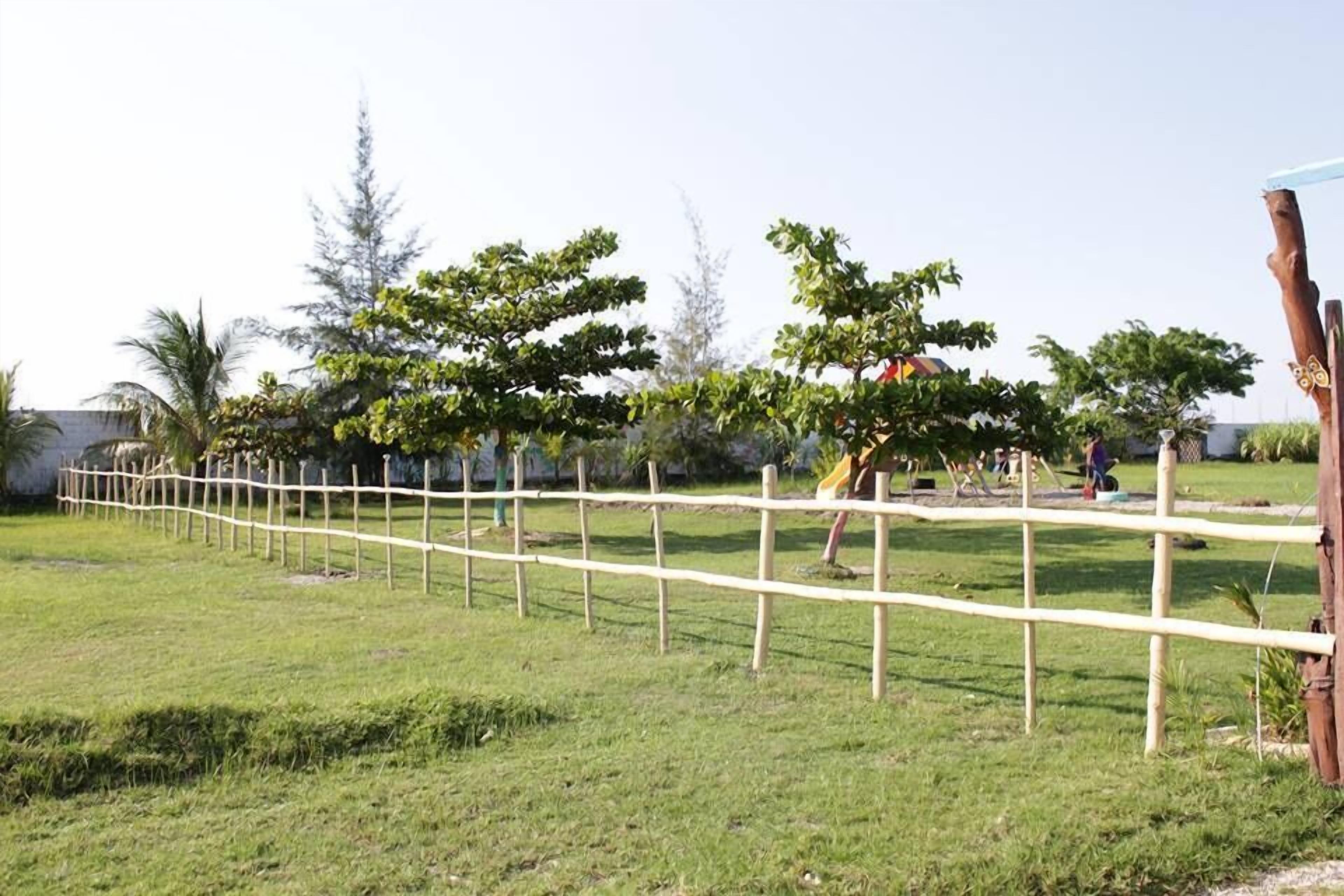 A fenced outdoor area with trees and a playground.