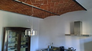 A kitchen with a brick ceiling, a hanging light fixture, a stainless steel range hood, and a built-in oven. - Farmhouse on an Organic Farm (Carmignano)