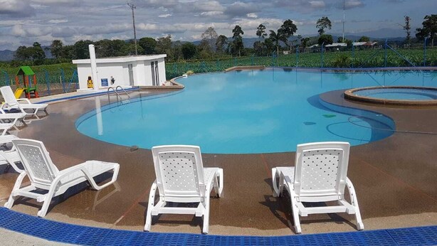 A swimming pool with white lounge chairs and a small building in the background.