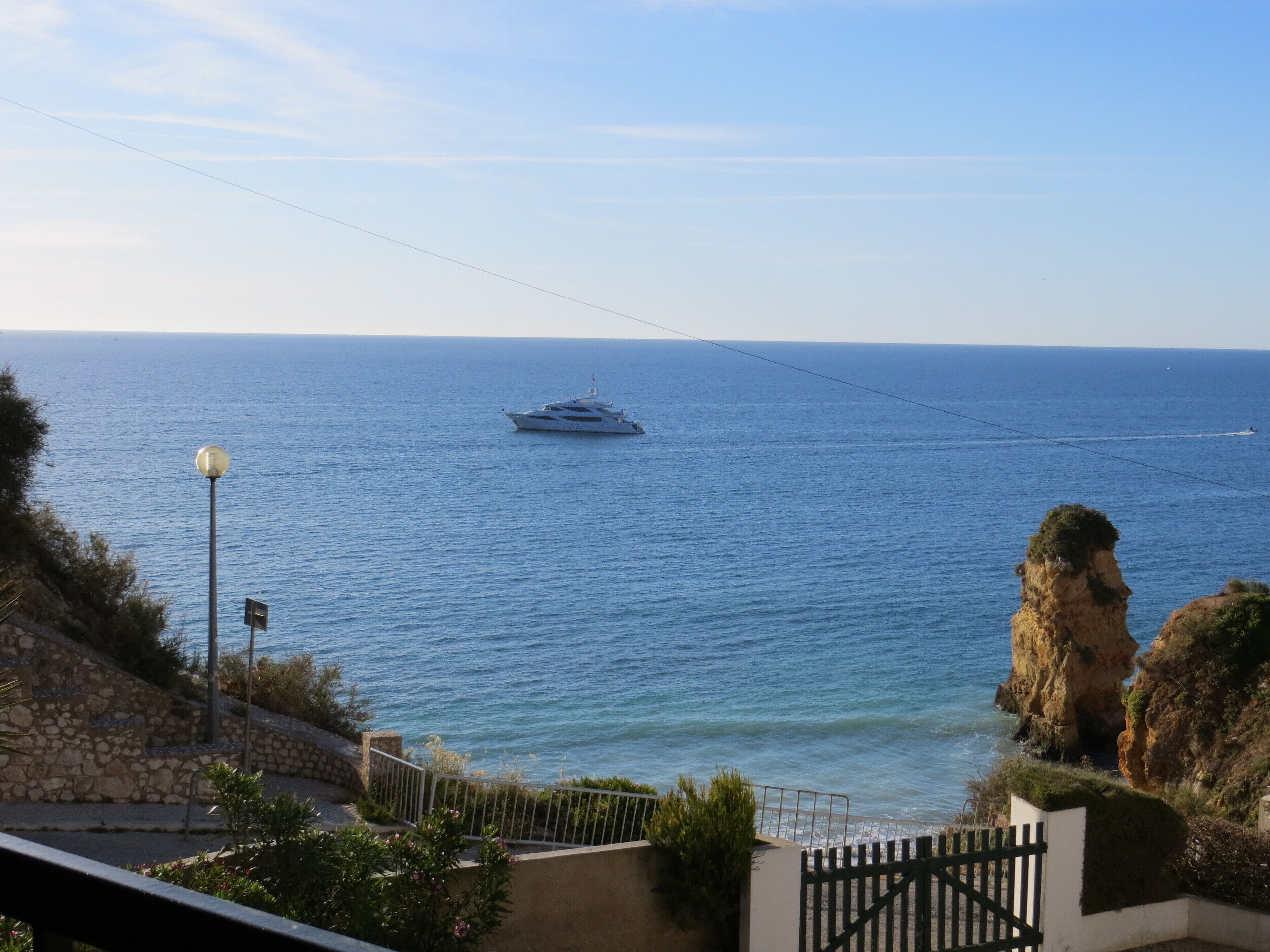Une vue sur la côte, avec un yacht sur l’eau, un escalier en pierre et une falaise rocheuse.