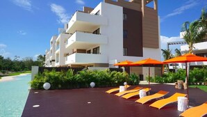 Een modern hotel met een zwembadgedeelte, inclusief ligbedden en oranje parasols.