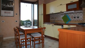 Una cocina con armarios de madera, una mesa de comedor con sillas y un ventanal.