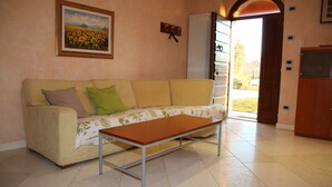 Un salón con un sofá color beige, una mesa de centro de madera y un cuadro de girasoles en la pared.