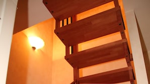 Una escalera en espiral de madera con un aplique de luz colgando.