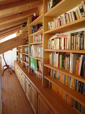 Een houten interieur met boekenplanken vol boeken, houten kastjes en een girafbeeld.