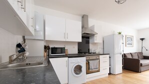 A modern kitchen with white cabinets, a built-in washing machine, and a refrigerator. - Modern Apartment "Woodleigh" Sleeps 4 (London)